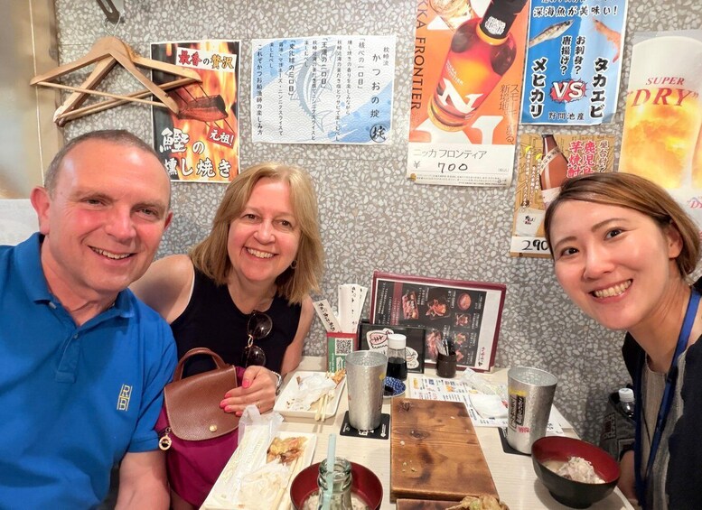 A group of people at a restaurant with various food items and drink bottles on the table. 4