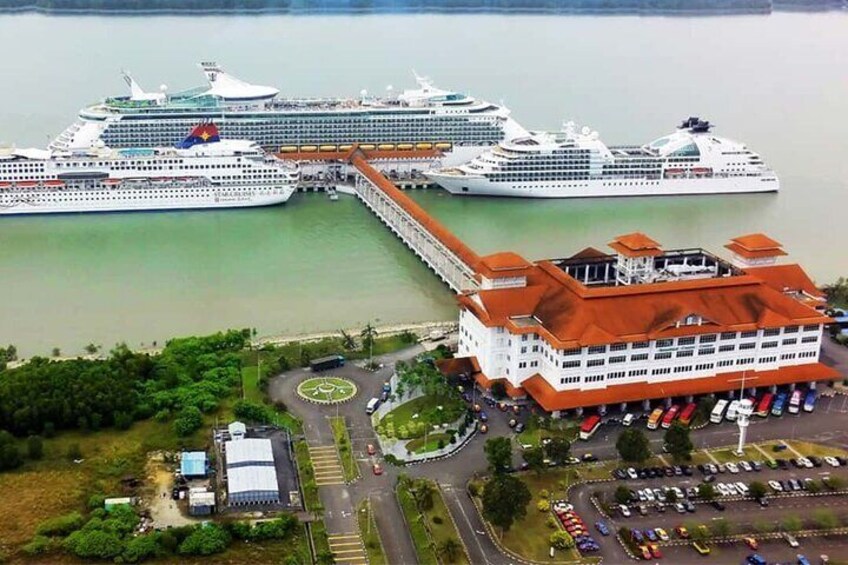 A cruise ship docked at a port with a large building nearby. 1