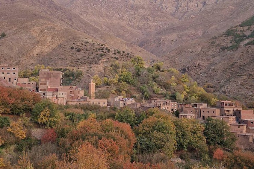 Un village niché dans une région montagneuse, avec des bâtiments traditionnels et un minaret imposant. 1