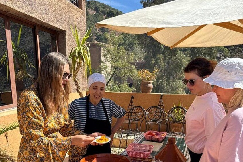 Un groupe de personnes est réuni autour d’une table dressée pour un repas en plein air, entouré de plantes et bénéficiant d’une vue pittoresque. 5