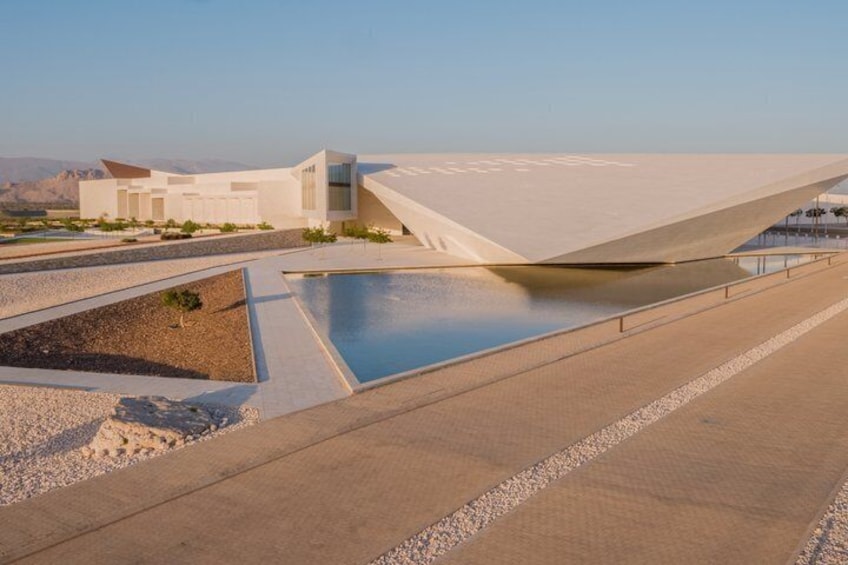 A modern architectural structure with a reflective pool and a desert landscape. 4