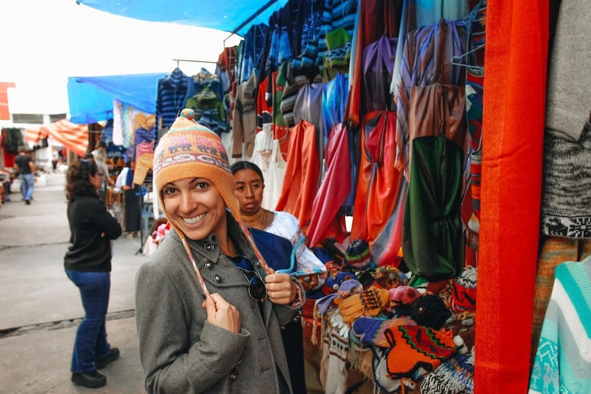 A market stall with colorful textiles and a person wearing a patterned hat. 2