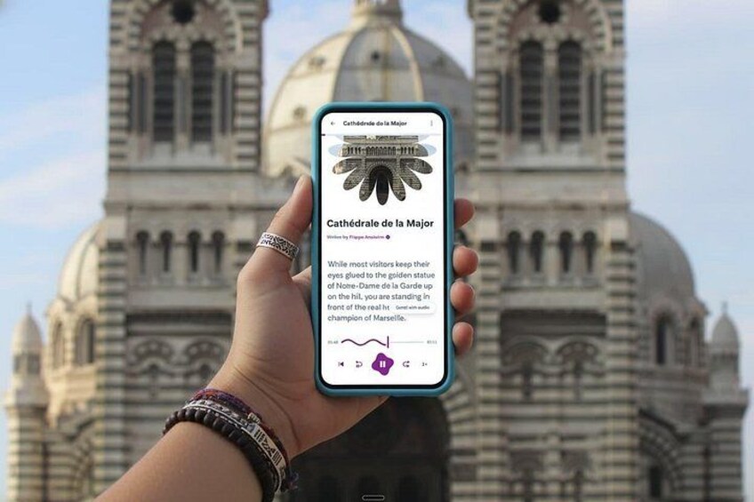 En hånd holder en smartphone med et katedral i baggrunden. 1