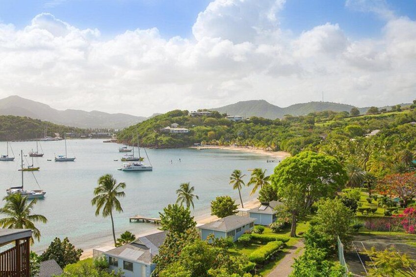 A coastal landscape with sailboats, a beach, and lush greenery. 1