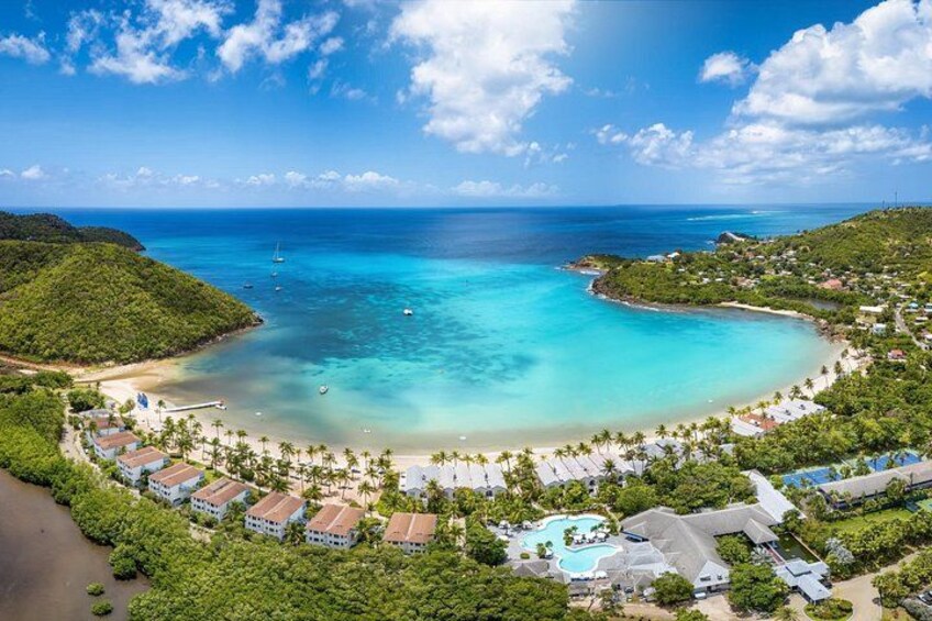A coastal resort with a clear blue sea, a sandy beach, and lush greenery. 4