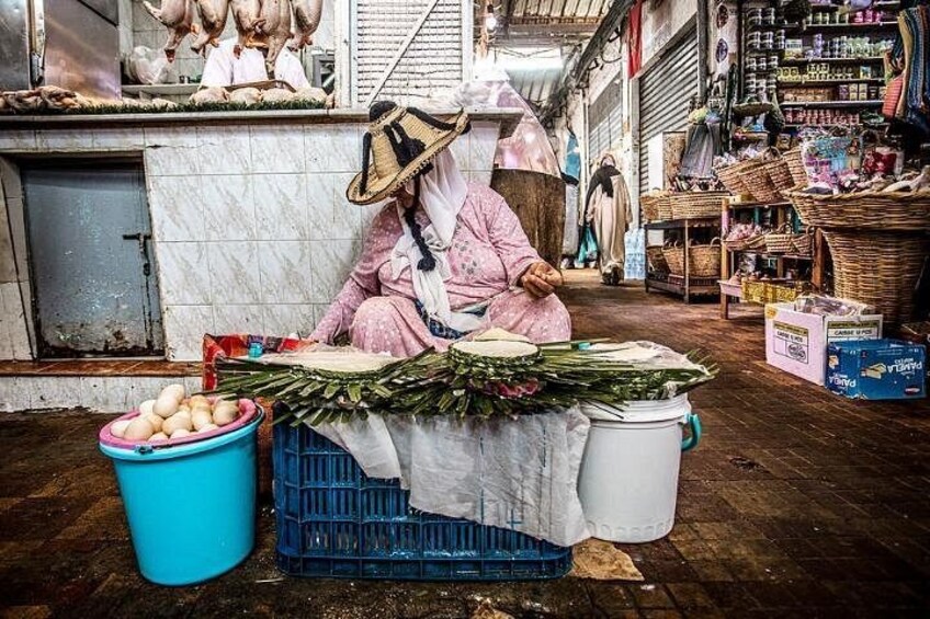Una bancarella di mercato con un venditore in abiti tradizionali che vende verdure e uova. 3