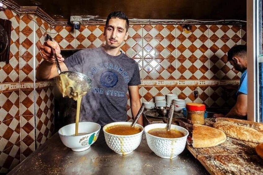 Una persona cucina in una cucina con pareti piastrellate e un bancone con ciotole e pane. 5