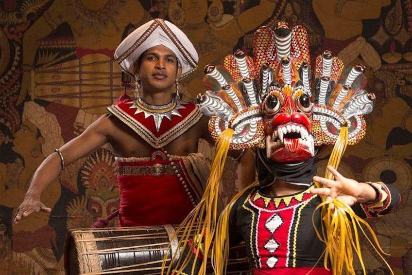 Deux personnes vêtues de costumes traditionnels et portant des coiffes élaborées, dont l’une joue du tambour. 1