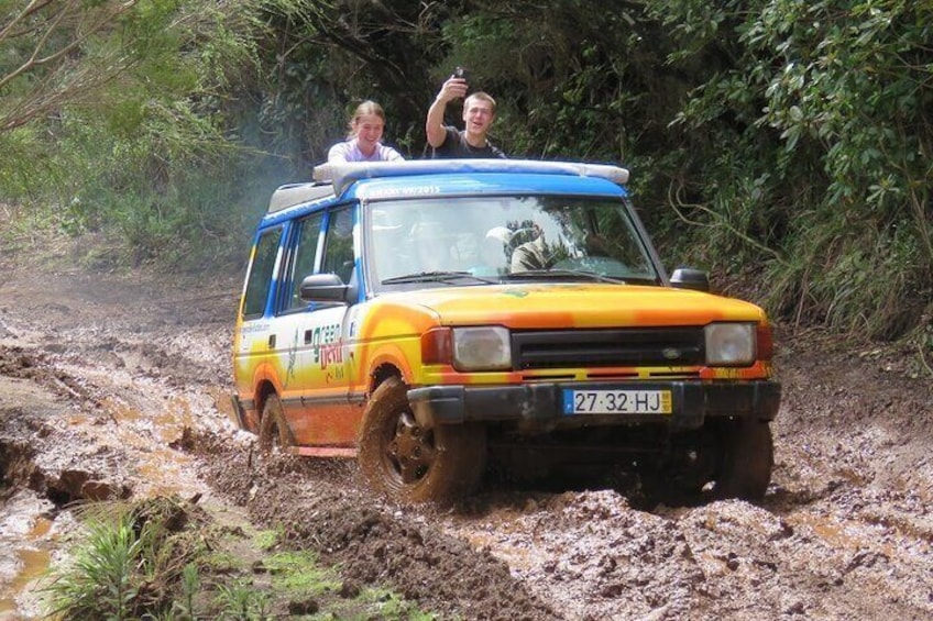 A yellow and blue off-road vehicle driving through a muddy terrain. 5