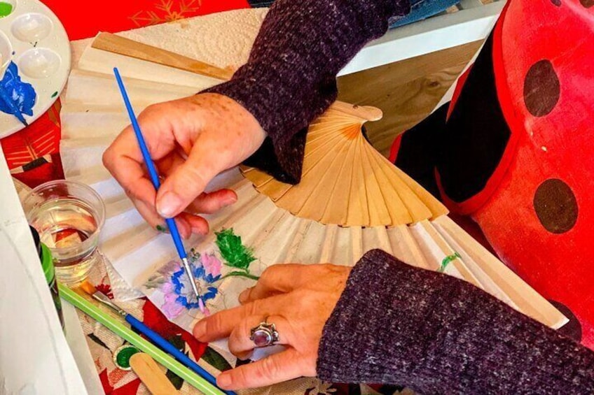 Una persona dipinge un ventaglio con decorazioni floreali. 4