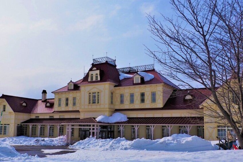 A large, historic building with a red roof and snow accumulation. 2