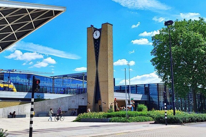 Un bâtiment moderne doté d’une tour horlogée, d’une piste cyclable et d’une zone piétonne agrémentée de verdure. 2