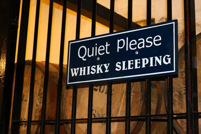 Un letrero con la inscripción 'Silencio, por favor. Whiskey durmiendo' en una reja metálica. 2