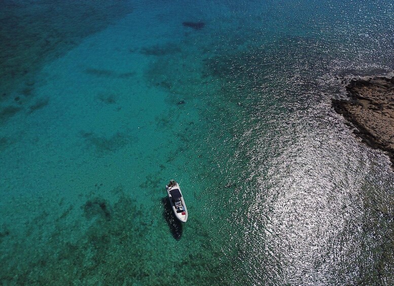 A boat on clear turquoise water near a rocky shoreline. 5