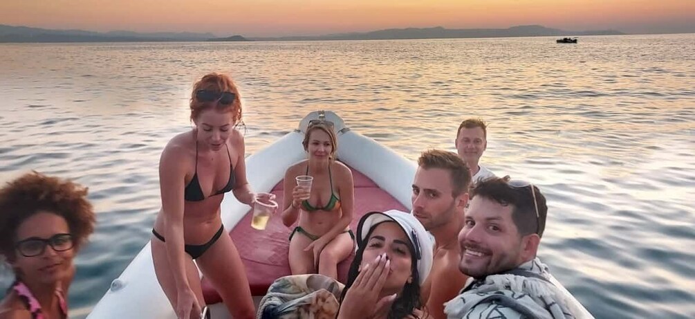 A group of people on a boat with a sunset in the background. 4