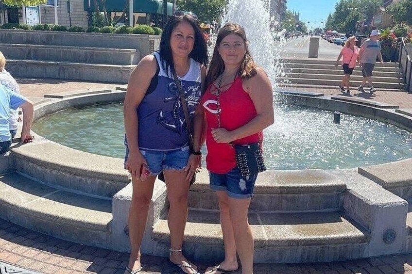 Dos mujeres de pie junto a una fuente con chorros de agua. 3