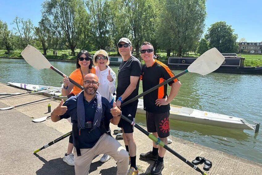 En gruppe mennesker står ved en flod med paddleboards og padler. 2