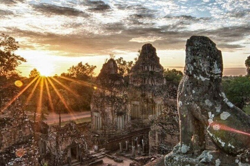 An ancient temple complex with a prominent stone statue and ruins bathed in sunlight. 1