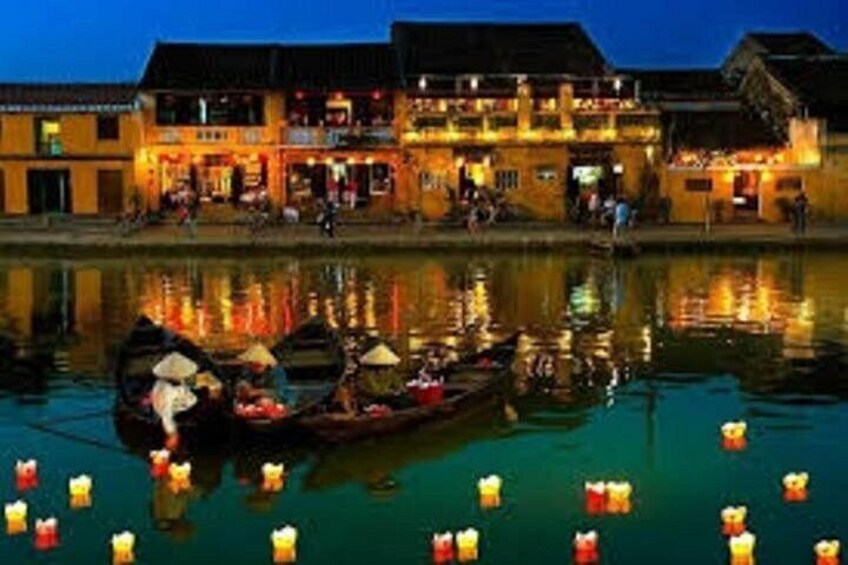 A riverside scene with traditional buildings and boats with canopies. 2