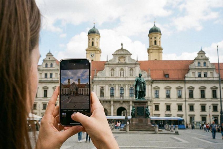 A person taking a photo of a historic building with a statue in front. 2