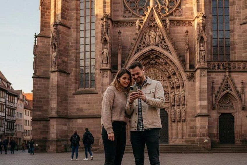 A couple taking a selfie in front of a Gothic-style church with intricate stonework and large windows. 3