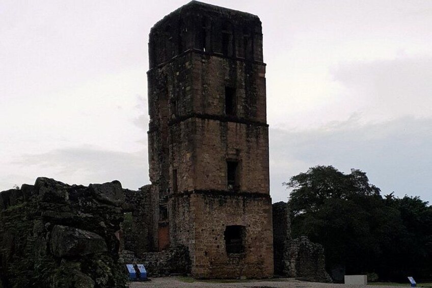 Ein hoher, verwitterter SteinTurm mit mehreren Ebenen, umgeben von felsigem Gelände und Bäumen. 4