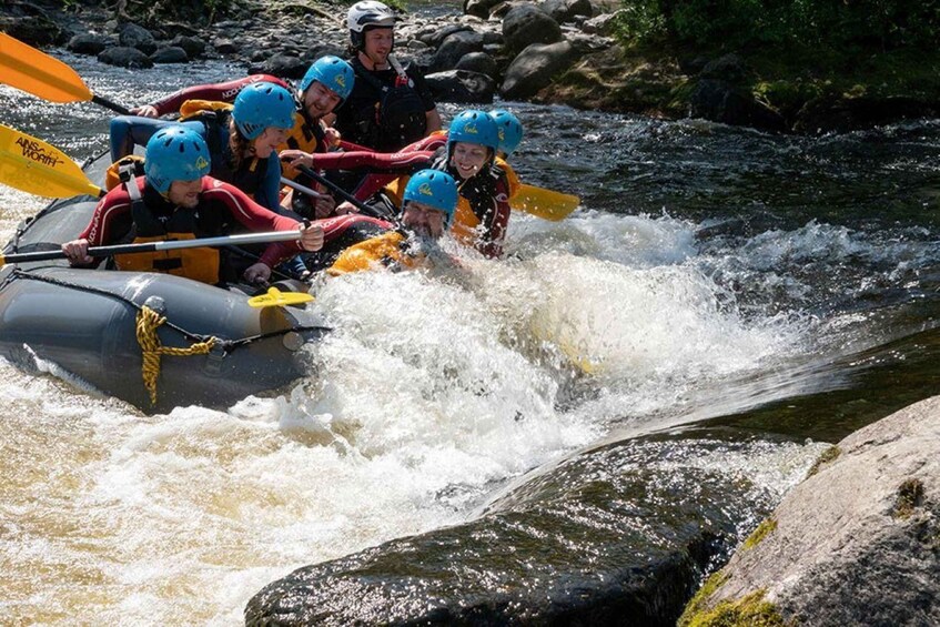 A group of people in a raft navigating a river with rapids. 1