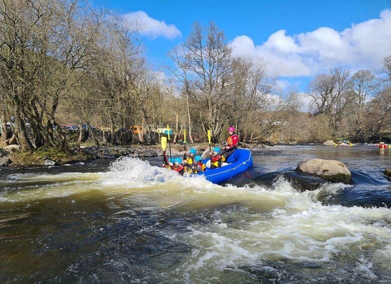 A group of people rafting down a river surrounded by trees. 5