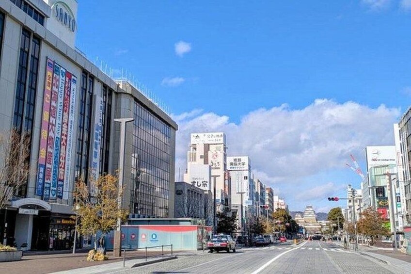 A city street with modern buildings, a clear sky, and a few cars on the road. 3