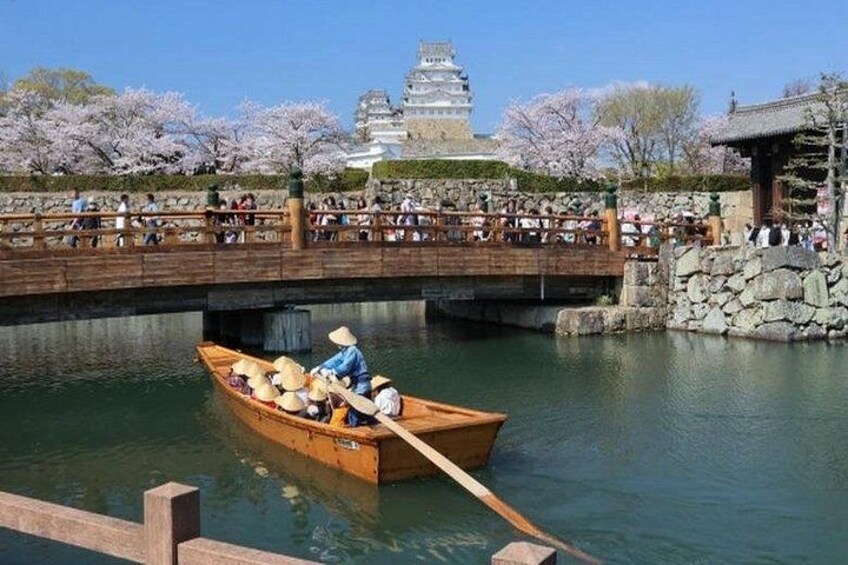 A traditional wooden boat on a calm river, a stone bridge, and a pagoda-like building in the background. 4