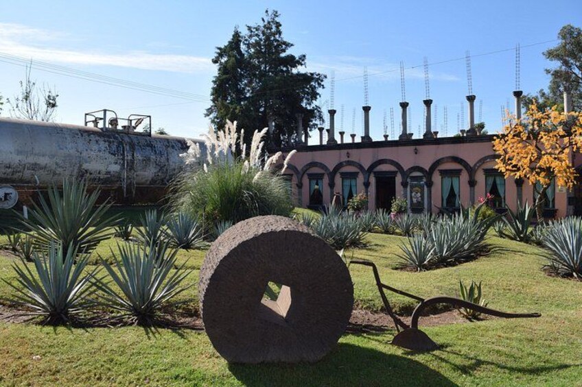 A large stone sculpture in a garden with a building in the background. 1