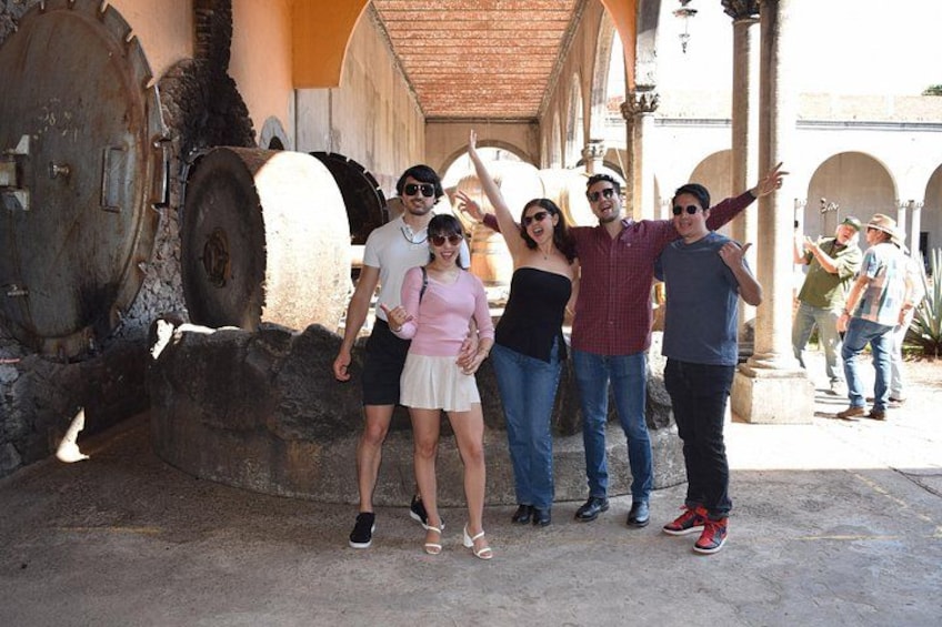 A group of people posing in front of a historical building with large stone wheels and arches. 4