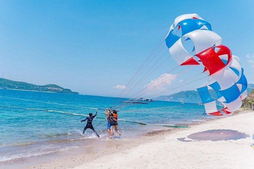 A beach with a large kite, a person running, and the sea. 2