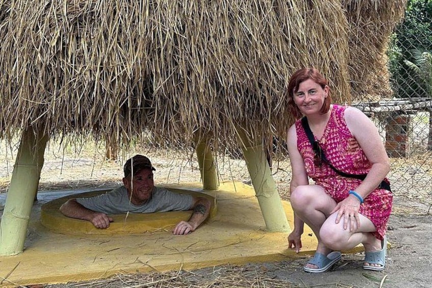 A man and a woman under a thatched structure, possibly a hut, with a yellow platform in front. 1
