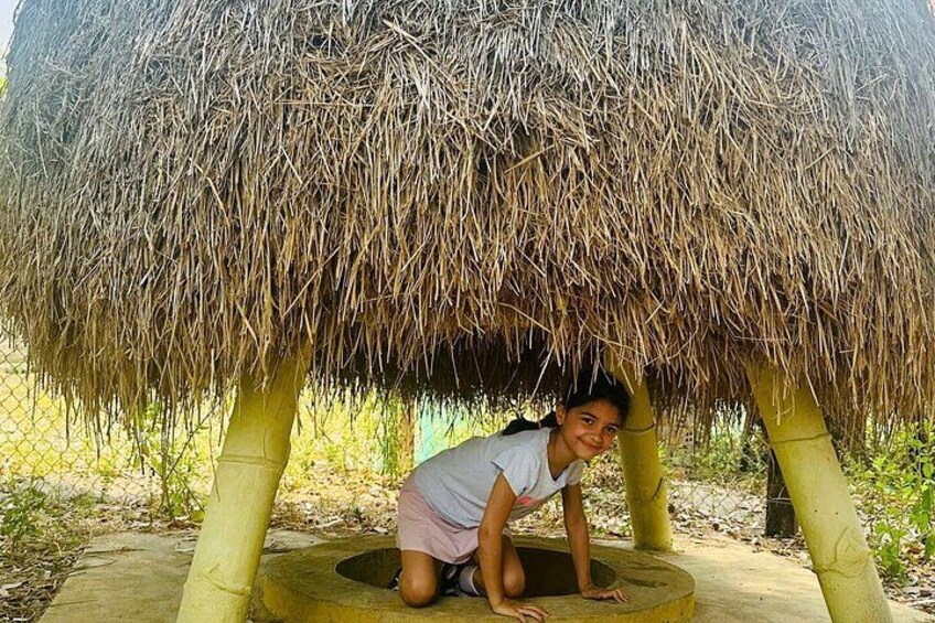 A person crouching under a thatched structure with a circular base. 3