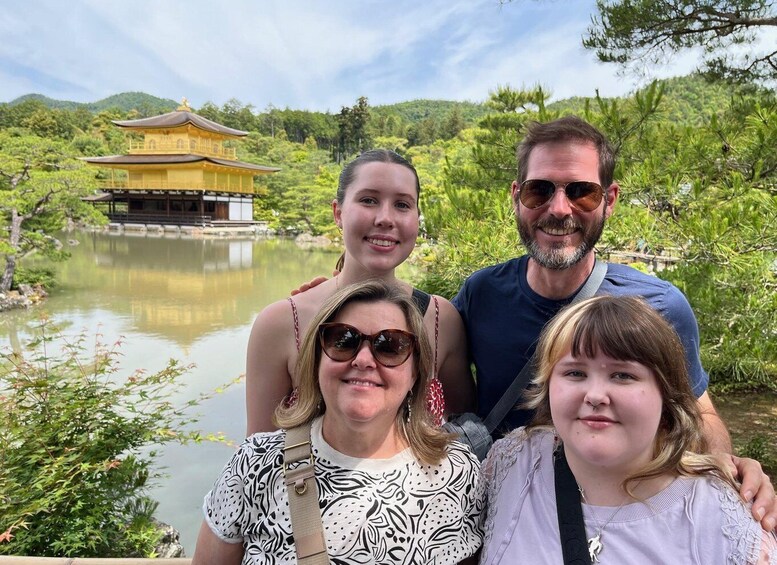 A family in front of a traditional building by a calm lake with lush greenery. 5