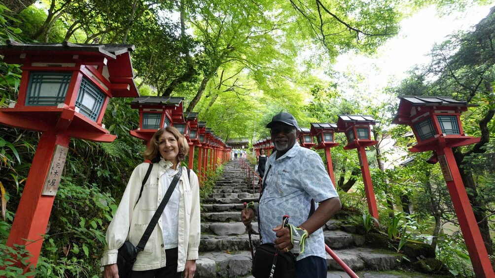 A pathway flanked by red torii gates, leading through a lush green forest. 2