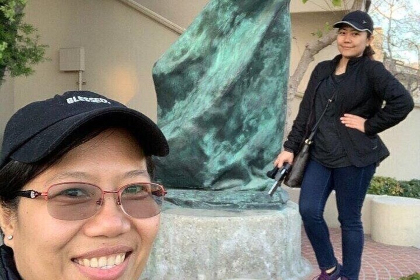 Una persona de pie junto a una estatua con rostro borroso. 5