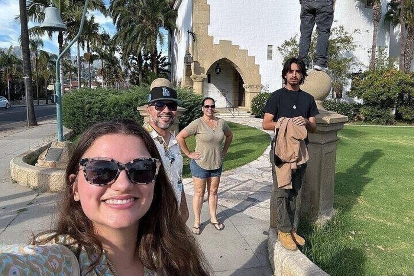 Un grupo de personas de pie frente a un edificio con una estatua en la parte superior. 4