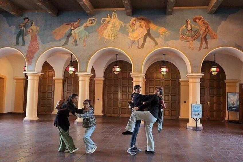 Un vestíbulo con columnas de arco, un mural y un letrero. 2