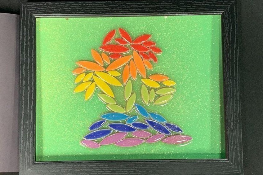 A framed artwork of colorful flowers on a green background. 2