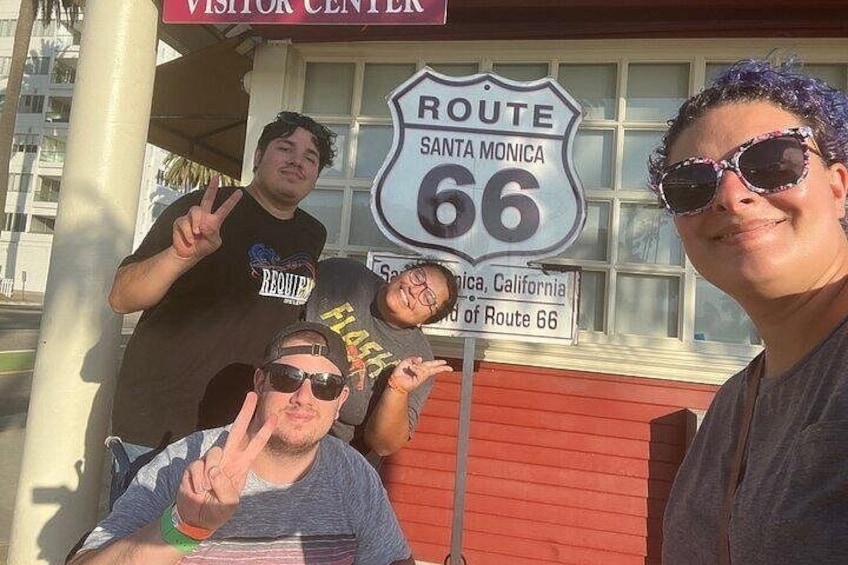 A group of people posing in front of a Route 66 sign. 1