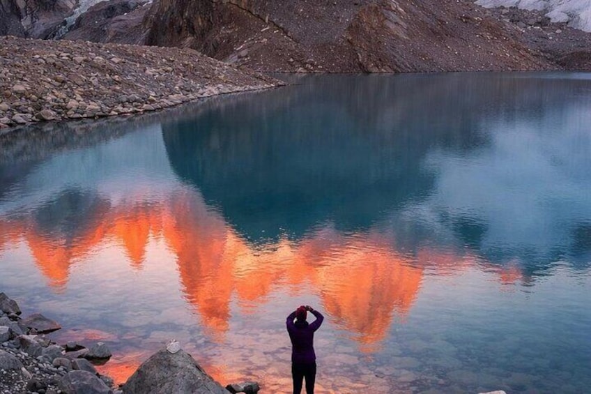 A person taking a photo of a lake with a reflection of the sky. 2