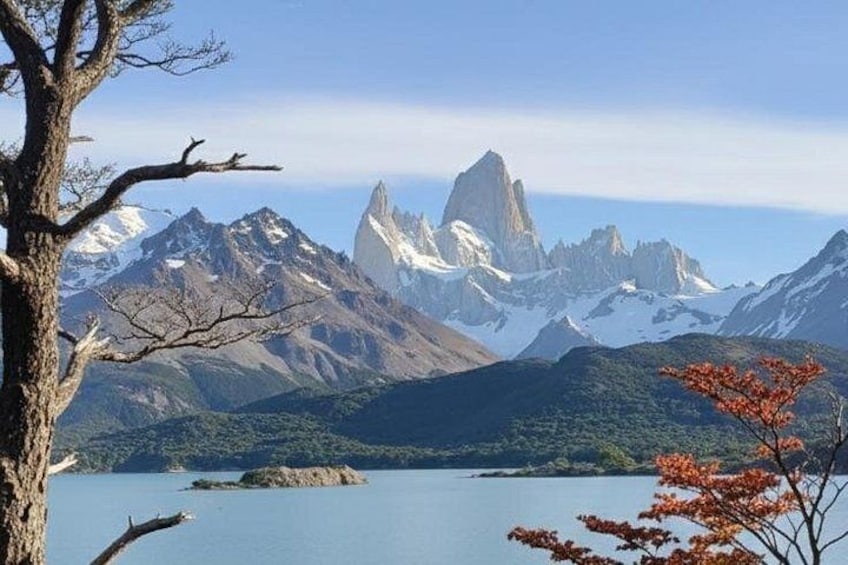 A mountainous landscape with a lake, a prominent peak, and a tree with autumn leaves. 3