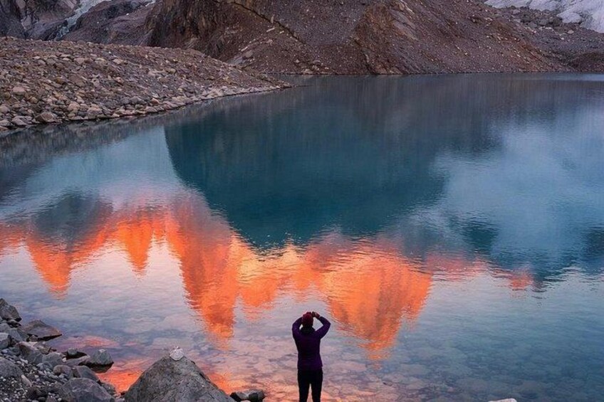A person standing by a calm lake with a reflection of the sky. 2