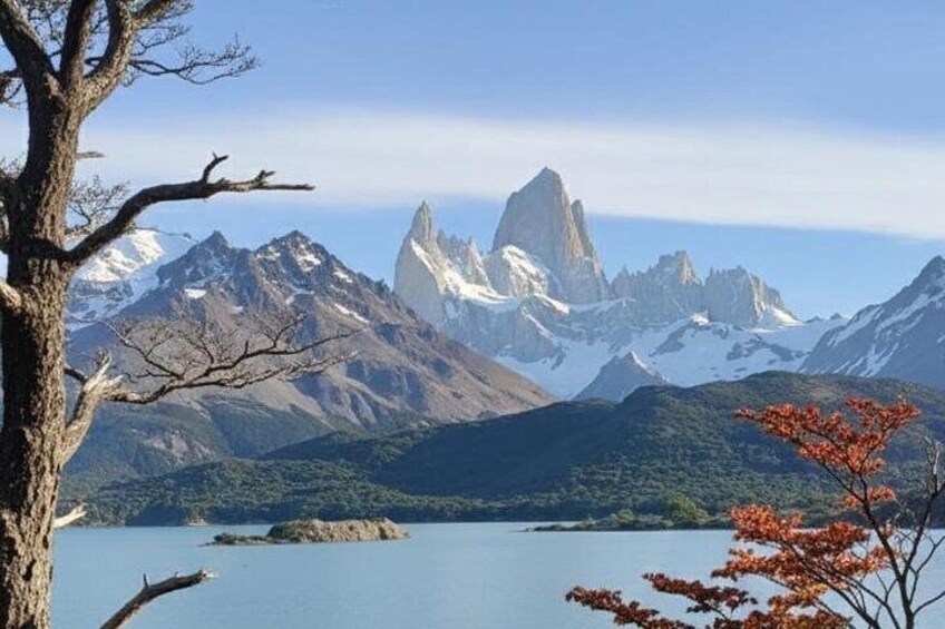 A mountainous landscape with a prominent peak, a body of water, and a tree with autumn leaves. 3