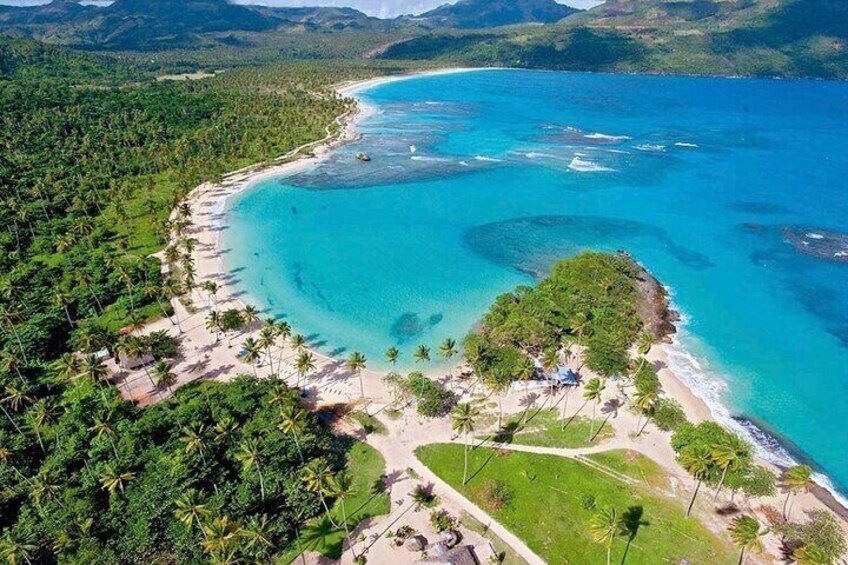 A tropical beach with clear turquoise waters, a small island, and lush greenery. 1