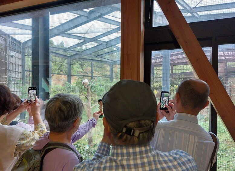 People taking photos through a large window at a zoo. 2