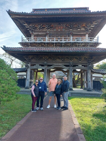 A traditional wooden pavilion with intricate carvings and a tiled roof, surrounded by greenery. 3