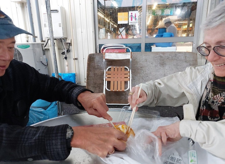 Two people eating at a table with a plastic bag and chopsticks. 5